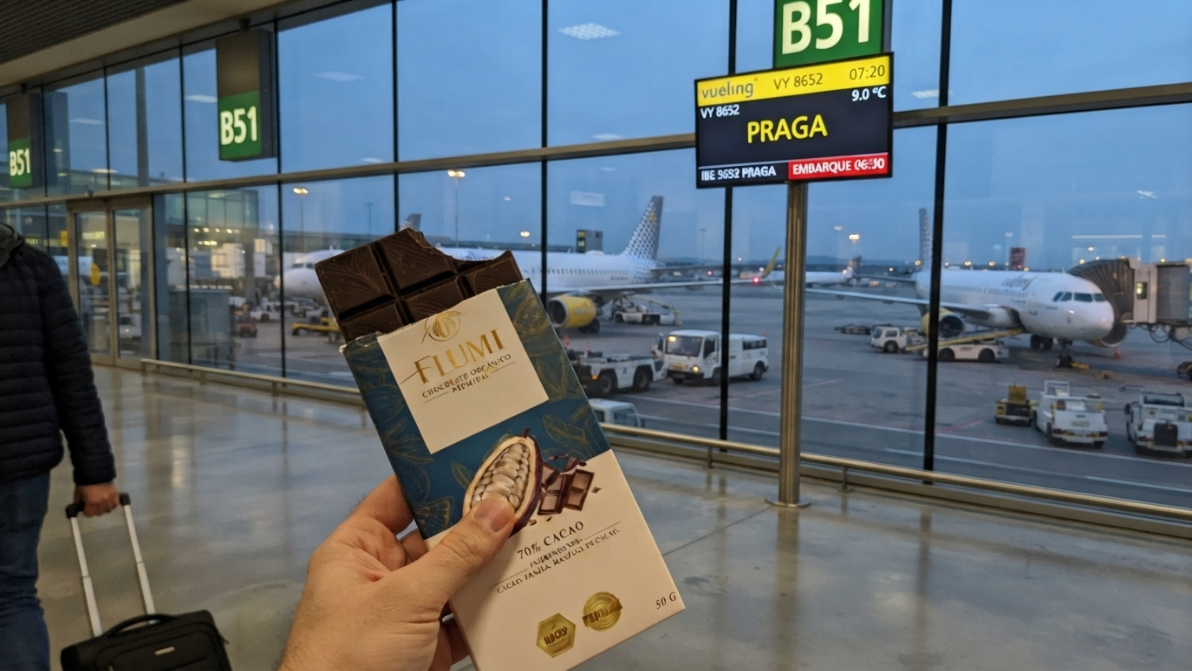 Chocolate Flumi en el aeropuerto junto a la pantalla de embarque con destino Praga
