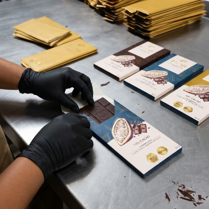 Manos con guantes empacando barras de chocolate Flumi